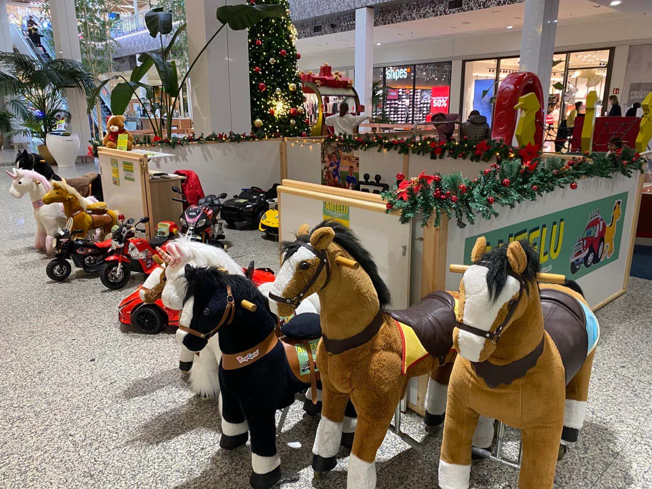 O posto de Antelu con coches, motos e cabaliños no centro comercial