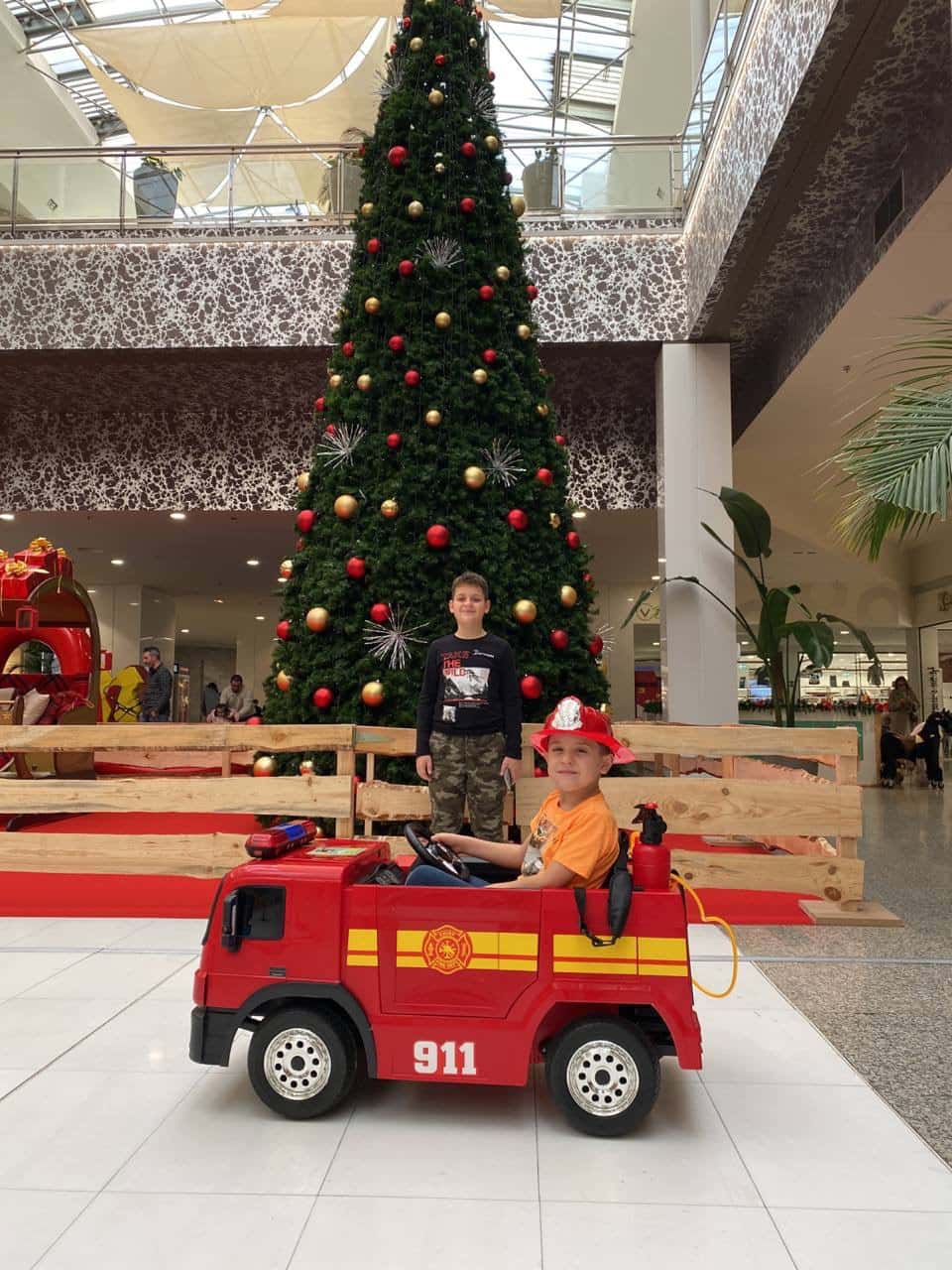 Camión de bombeiros infantil xunto á árbore de Nadal do centro comercial